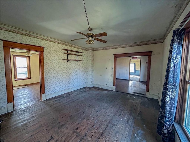 unfurnished room featuring ornamental molding, dark wood-type flooring, wallpapered walls, a wealth of natural light, and ceiling fan
