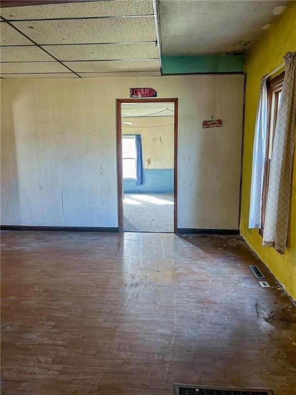 empty room with visible vents, wooden walls, and wood finished floors