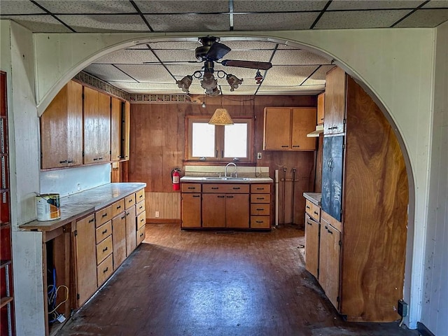 kitchen featuring brown cabinets, arched walkways, a sink, and a ceiling fan