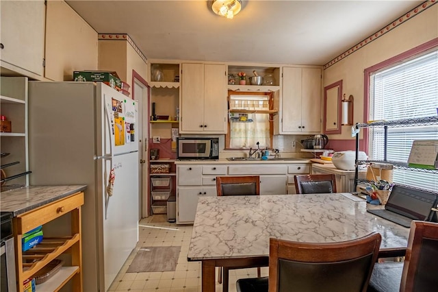 3939 NE Court Dr, Decatur, IL 62526 - kitchen with stainless steel microwave, a peninsula, light countertops, open shelves, and light floors