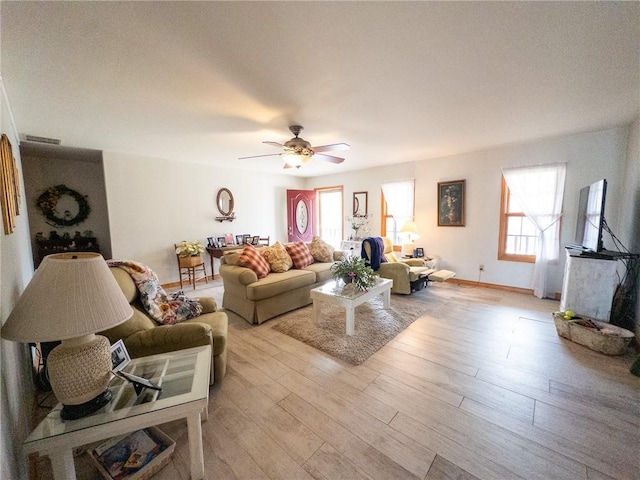 living room with light wood finished floors, plenty of natural light, baseboards, and ceiling fan