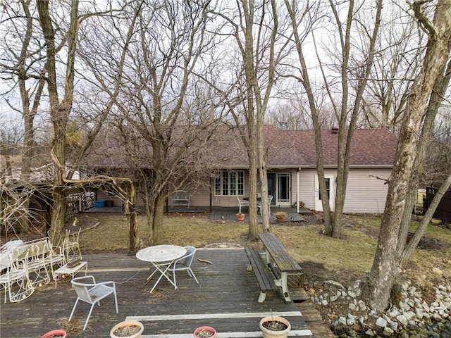 back of house with roof with shingles and a wooden deck