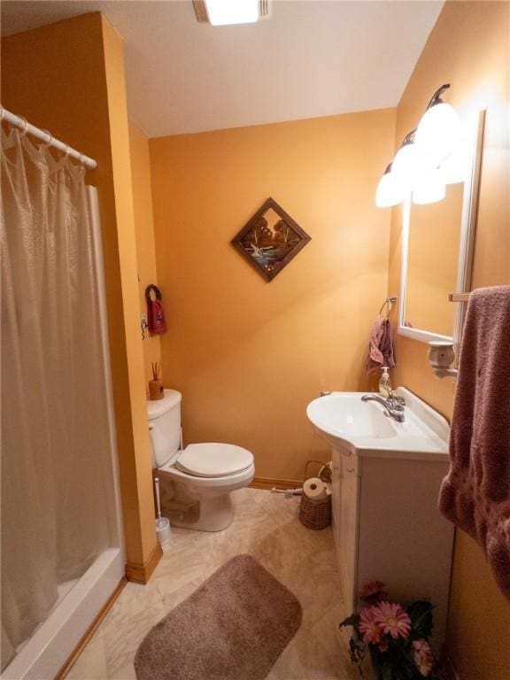 bathroom with baseboards, toilet, a stall shower, and vanity