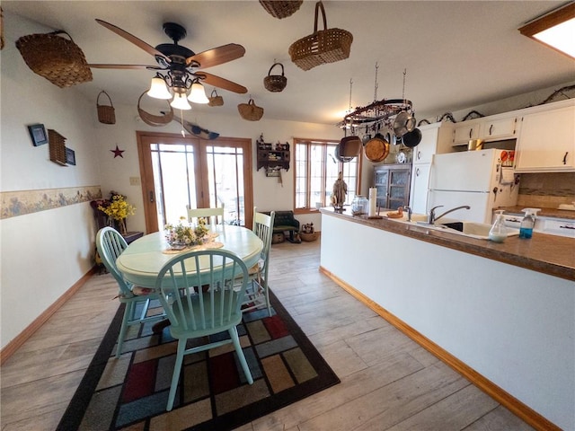 unfurnished dining area featuring a ceiling fan, light wood-style floors, and baseboards