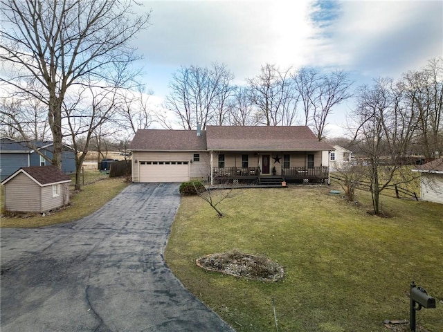 single story home featuring a front lawn, aphalt driveway, a porch, a garage, and an outdoor structure