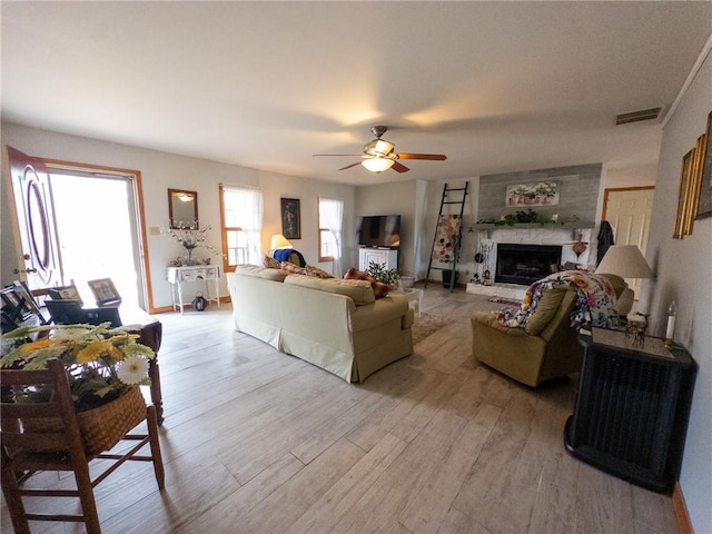 living room with visible vents, a healthy amount of sunlight, a fireplace, and light wood finished floors