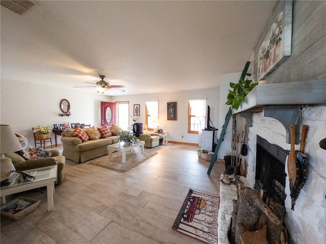 living area with wood finished floors, baseboards, visible vents, a fireplace, and ceiling fan