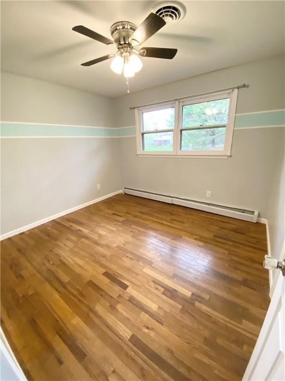 unfurnished room with a baseboard heating unit, baseboards, visible vents, wood finished floors, and ceiling fan