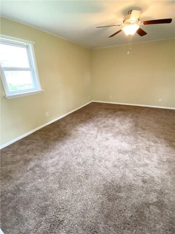carpeted spare room with a ceiling fan and baseboards
