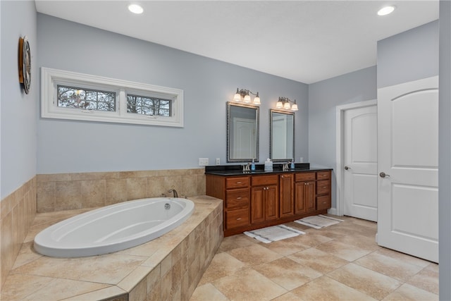 bathroom with tile patterned flooring, vanity, and a relaxing tiled tub