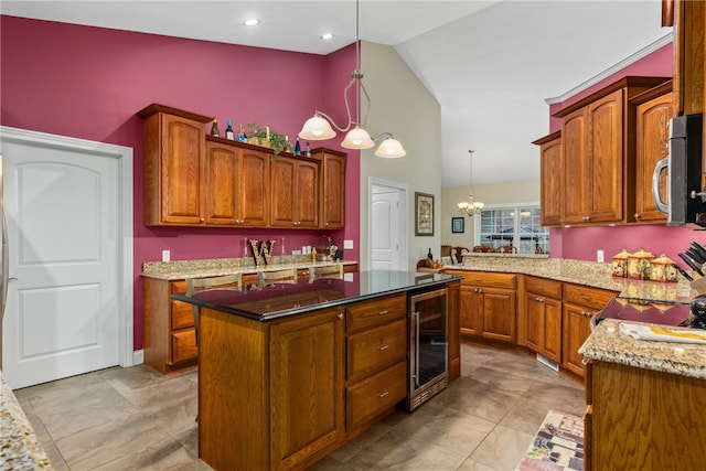 kitchen featuring hanging light fixtures, wine cooler, light stone counters, a notable chandelier, and a kitchen island