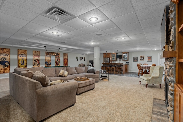 carpeted living room with a drop ceiling and bar