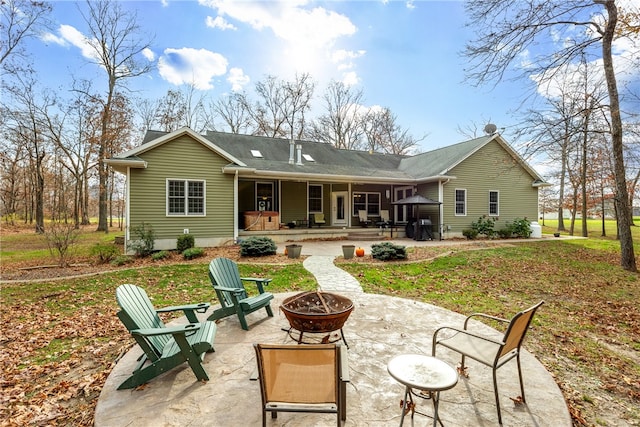 rear view of property featuring a patio area, a yard, and a fire pit