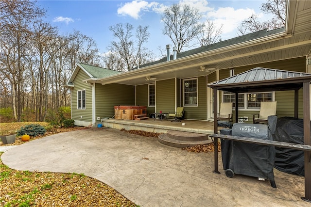 rear view of house featuring a gazebo, a hot tub, and a patio area