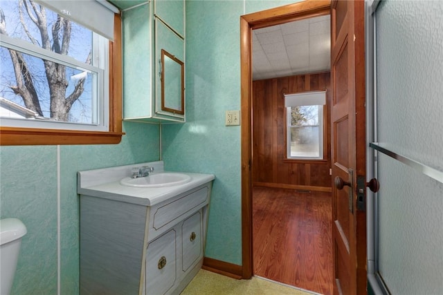 half bath with baseboards, toilet, and vanity