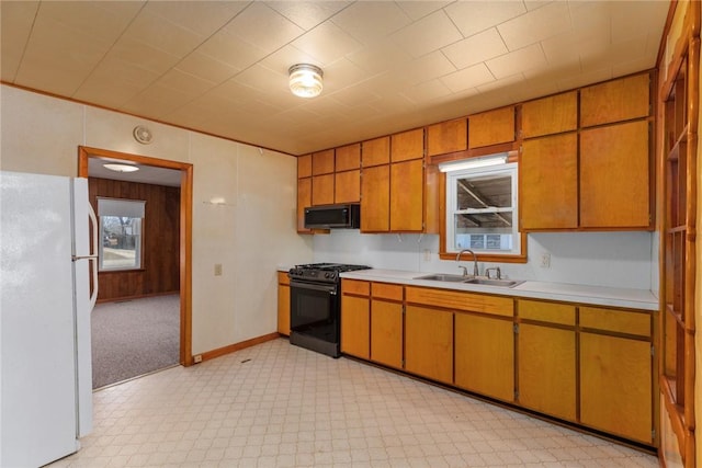 kitchen featuring light floors, light countertops, freestanding refrigerator, gas stove, and a sink