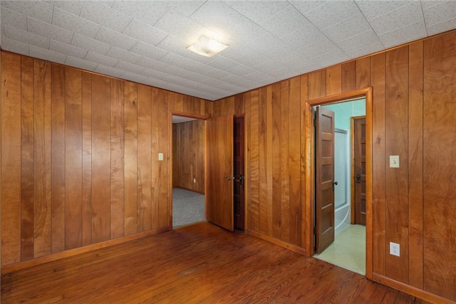 empty room with wooden walls, baseboards, and wood finished floors