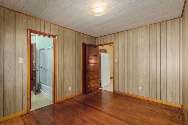 empty room with wood walls, baseboards, and hardwood / wood-style flooring