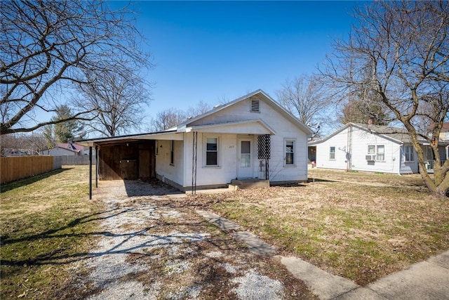 view of front of property featuring an attached carport, fence, a front lawn, and driveway