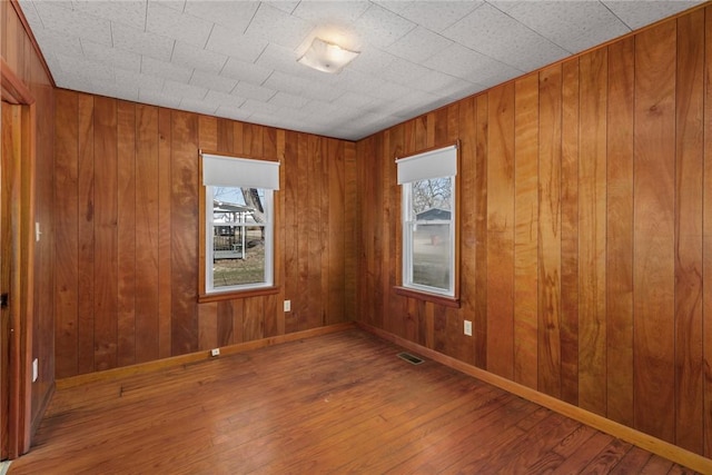 spare room with wood finished floors, visible vents, and a wealth of natural light