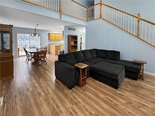 living room with a high ceiling, a chandelier, and light hardwood / wood-style flooring