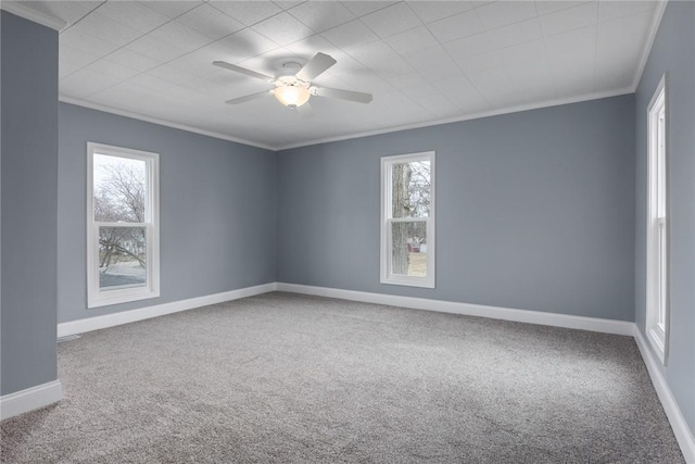 carpeted spare room featuring ornamental molding, plenty of natural light, a ceiling fan, and baseboards