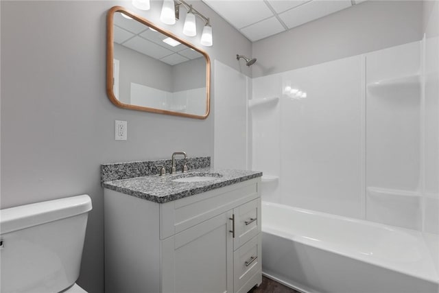 bathroom featuring  shower combination, a drop ceiling, vanity, and toilet