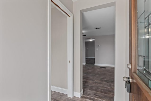 hallway featuring dark wood-style floors, visible vents, and baseboards