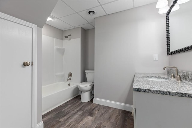 bathroom with shower / bathtub combination, a paneled ceiling, toilet, wood finished floors, and vanity