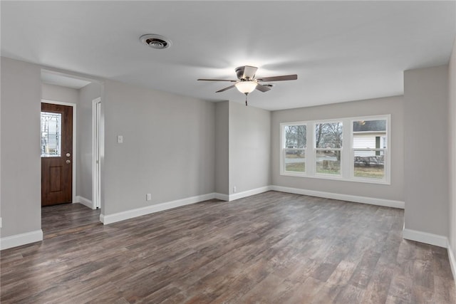 empty room with a wealth of natural light, baseboards, and dark wood-type flooring