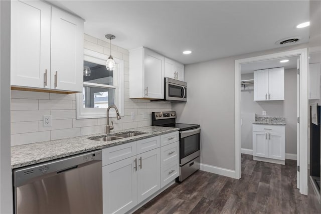 kitchen featuring white cabinetry, stainless steel appliances, a sink, and decorative light fixtures