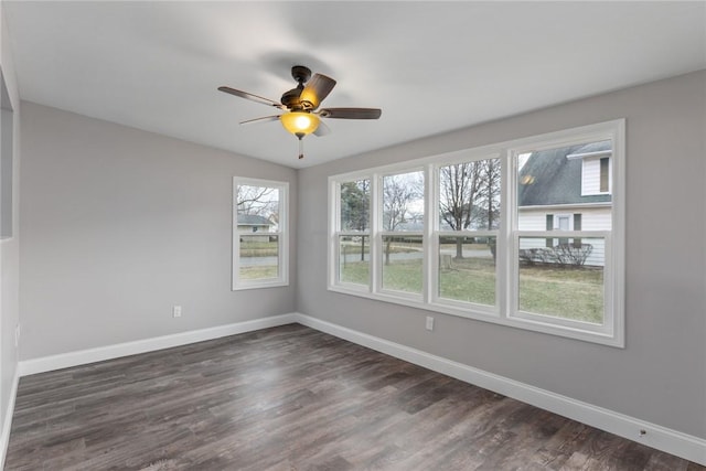 spare room with dark wood-style flooring, a ceiling fan, and baseboards