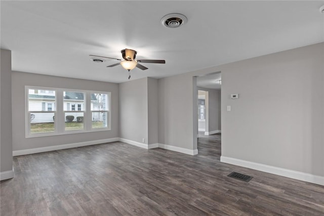 spare room featuring dark wood-style floors, visible vents, and baseboards