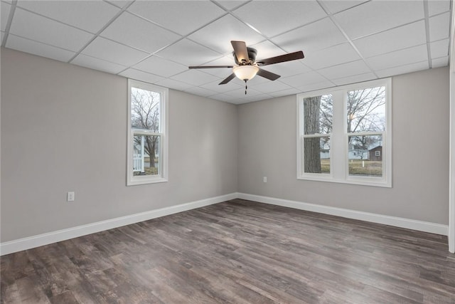 empty room with a paneled ceiling, dark wood-style flooring, and baseboards