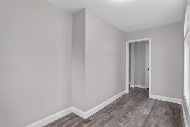 empty room with dark wood-style flooring and baseboards