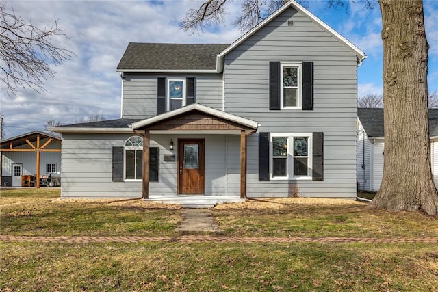 traditional home with a shingled roof, a porch, and a front yard