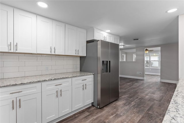 kitchen featuring tasteful backsplash, stainless steel fridge, white cabinets, dark wood-style floors, and light stone counters