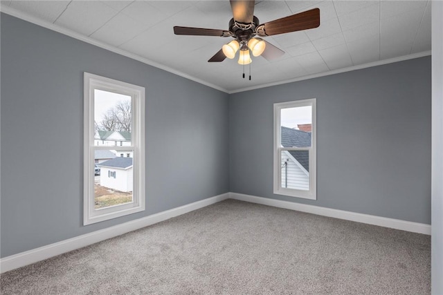 carpeted spare room featuring baseboards, ceiling fan, and crown molding