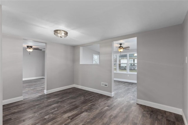 empty room with baseboards, visible vents, and dark wood-type flooring