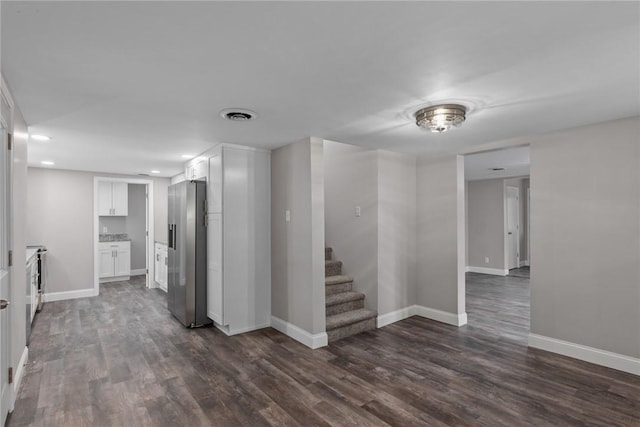 spare room with visible vents, dark wood finished floors, stairway, and baseboards