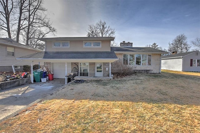 view of front of house with an attached garage, driveway, a chimney, and a front yard