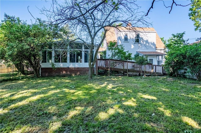back of house featuring a wooden deck, a lawn, and a sunroom