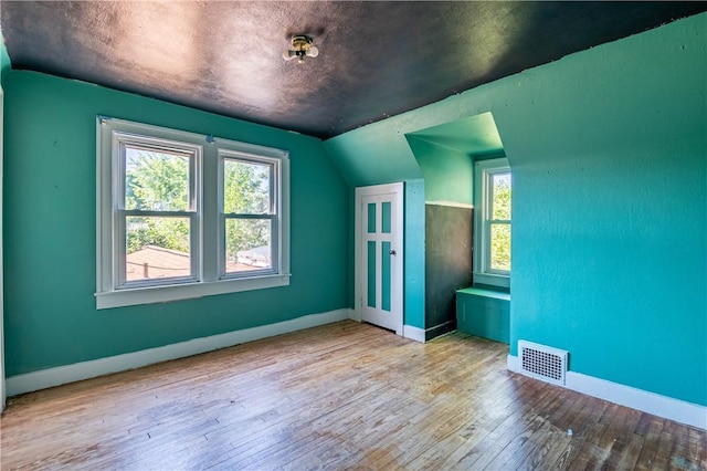 additional living space with lofted ceiling, hardwood / wood-style floors, baseboards, and healthy amount of natural light