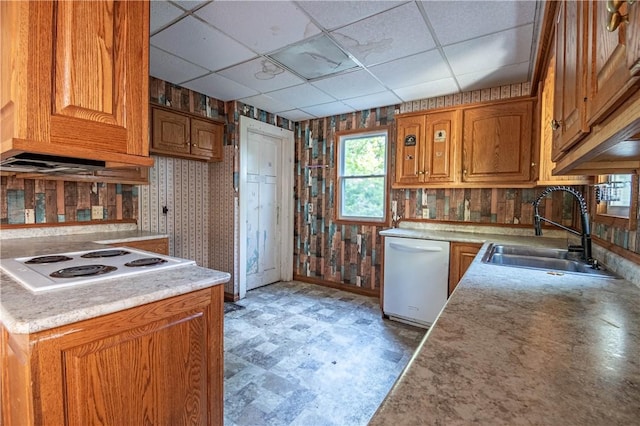 kitchen with white appliances, a sink, light floors, wallpapered walls, and a paneled ceiling