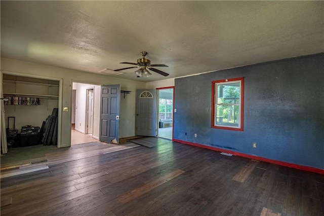 unfurnished living room featuring hardwood / wood-style floors, baseboards, ceiling fan, and a textured ceiling