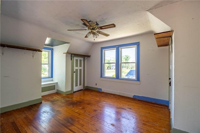 additional living space with wood-type flooring, ceiling fan, plenty of natural light, vaulted ceiling, and baseboards