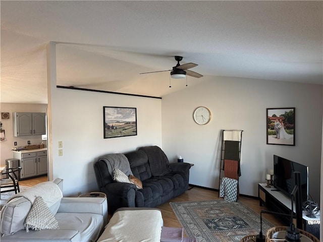 living room featuring lofted ceiling, wood finished floors, and a ceiling fan