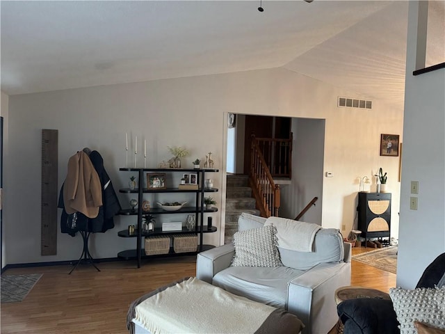 living room with vaulted ceiling, wood finished floors, stairs, and visible vents