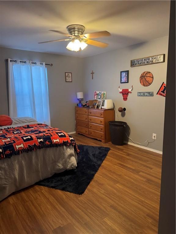 bedroom with a ceiling fan, baseboards, and wood finished floors