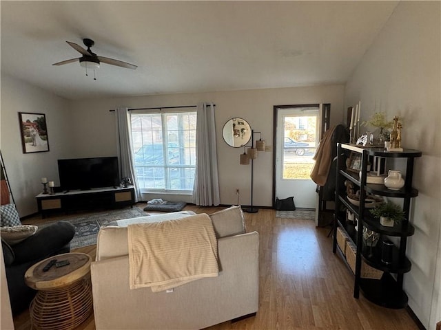 living area with a ceiling fan, a healthy amount of sunlight, vaulted ceiling, and wood finished floors